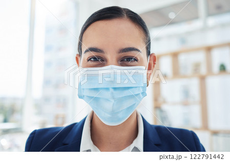 Safety, compliance and face mask covid regulations at work with a young employee in an office. Corporate professional smiling and looking positive, enjoying her career and hygiene at the workplace 122791442