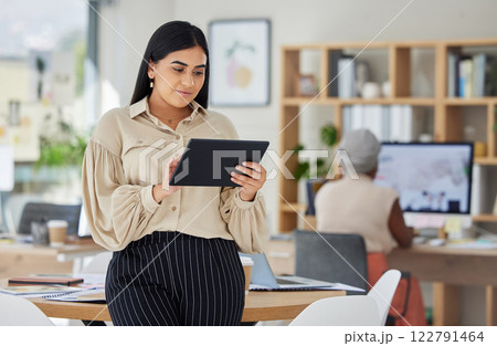 Business woman, office and working on digital tablet in the workplace with colleague in the background. Happy employee busy with online marketing on touchscreen in research, development and design. Business woman, office and working on digital tablet in the workplace with colleague in the background. Happy employee busy with online marketing on touchscreen in research, development and design. 122791464