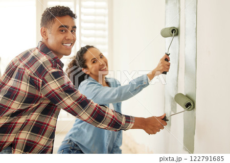 Happy couple painting for renovation with a brush in the living room at home. Portrait of a creative man and woman with a smile add paint on wall in the lounge for home improvement and maintenance 122791685