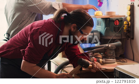 Man carving intricate designs into wood using chisel and hammer in carpentry shop, enjoying diy hobby. Woodworking specialist in studio shaping wooden pieces with tools, making wood art, camera A Man carving intricate designs into wood using chisel and hammer in carpentry shop, enjoying diy hobby. Woodworking specialist in studio shaping wooden pieces with tools, making wood art, camera A 122791810