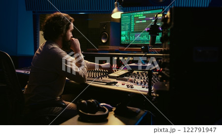 Music producer fixing coiled cable inside amplifier or audio compressor, prepares control room technical equipment for a recording session. Sound engineer works on producing tracks. Camera B. 122791947