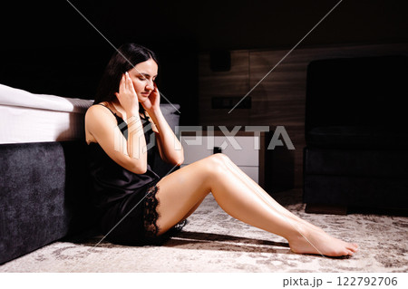 Unhappy woman touching hair, sitting on floor at home, thinking about problems. Upset girl feeling lonely and sad, psychological and mental troubles, suffering from bad relationship or break up 122792706