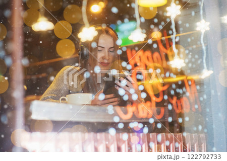 Young beautiful woman sitting in cafe, drinking coffee. Model listening to music. Christmas, Happy new year, Valentines day, winter holidays concept 122792733