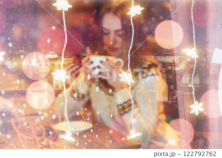 Young beautiful woman sitting in cafe, drinking coffee. Christmas, new year, winter holidays concept double exposure, night city 122792762