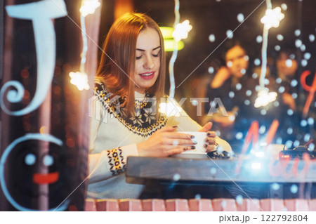 Young beautiful woman sitting in cafe, drinking coffee. Christmas, new year, Valentines day, winter holidays concept Young beautiful woman sitting in cafe, drinking coffee. Christmas, new year, Valentines day, winter holidays concept 122792804