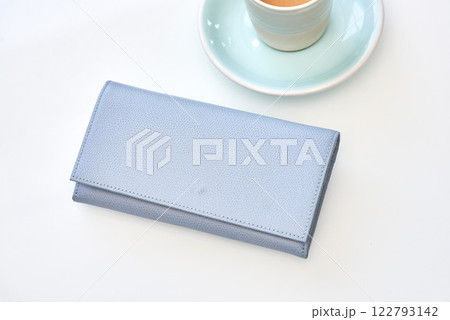 Stylish blue wallet resting near elegant espresso cup on white background, minimalist luxury fashion concept 122793142