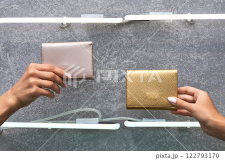 Elegant wallets in hands under modern lighting against gray backdrop, showcasing fashion and luxury, accessories concept Elegant wallets in hands under modern lighting against gray backdrop, showcasing fashion and luxury, accessories concept 122793170