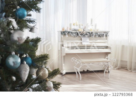 New Year decoration. Christmas tree near white piano at the window background New Year decoration. Christmas tree near white piano at the window background 122793368
