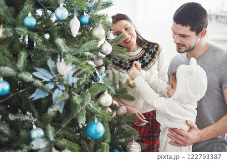 Happy Family Decorating Christmas Tree together. Father, Mother And Daughter. Cute Child Happy Family Decorating Christmas Tree together. Father, Mother And Daughter. Cute Child 122793387