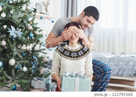Young couple celebrating Christmas. A man suddenly presented a present to his wife. The concept of family happiness and well-being 122793388
