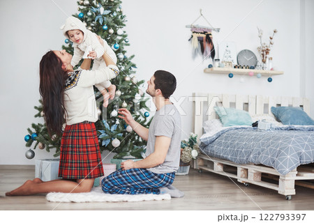 Happy family at christmas in morning opening gifts together near the fir tree. The concept of family happiness and well-being 122793397