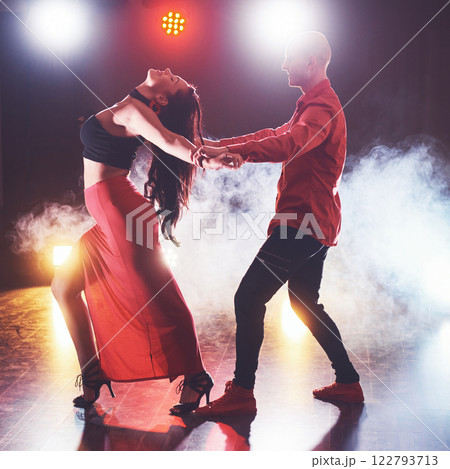 Skillful dancers performing in the dark room under the concert light and smoke. Sensual couple performing an artistic and emotional contemporary dance 122793713