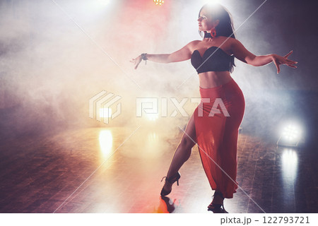Skillful and beautiful dancer girl performing in the dark room under the concert light and smoke, performing an artistic and emotional contemporary dance 122793721