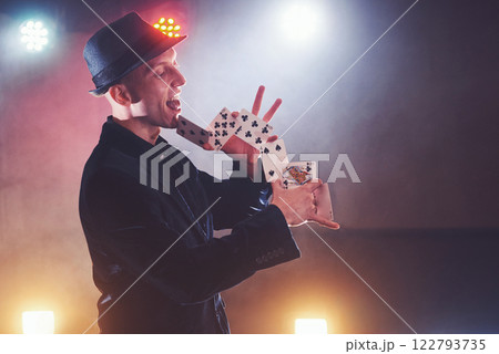 Magician showing trick with playing cards. Magic or dexterity, circus, gambling. Prestidigitator in dark room with fog 122793735