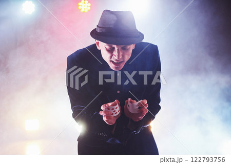 Magician showing trick with playing cards. Magic or dexterity, circus, gambling. Prestidigitator in dark room with fog Magician showing trick with playing cards. Magic or dexterity, circus, gambling. Prestidigitator in dark room with fog 122793756