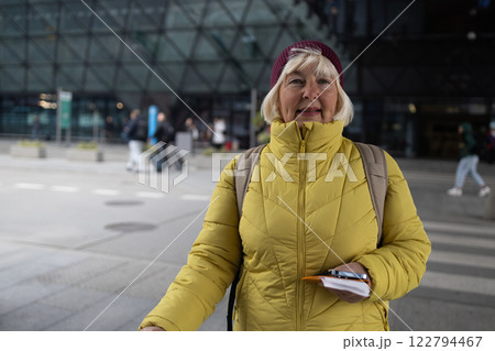 Senior female tourist in airport hold suitcase valise passport ticket schedule to check flight departure gate. Travel and tourism concept, people with backpack on shoulders. 122794467
