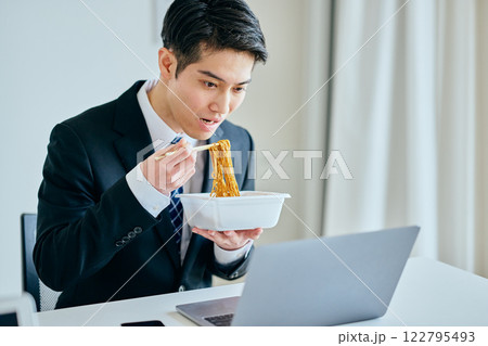 カップ焼きそばを食べながら仕事をする20代の若い男性 カップ焼きそばを食べながら仕事をする20代の若い男性 122795493