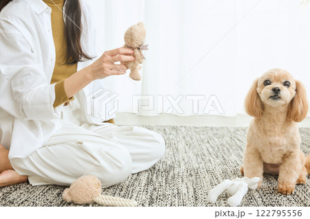 リビングで愛犬と遊ぶ女性 122795556