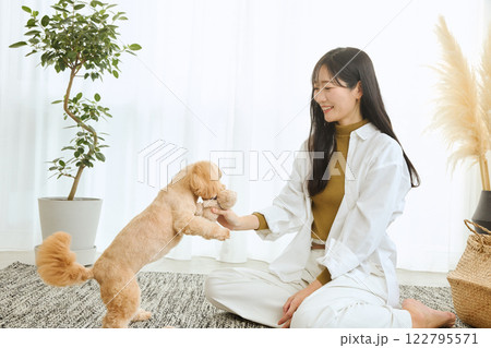 リビングで愛犬と遊ぶ女性 122795571