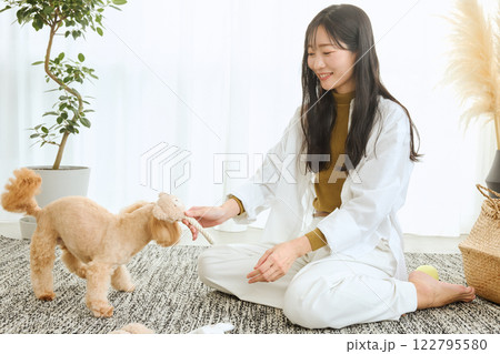 リビングで愛犬と遊ぶ女性 122795580