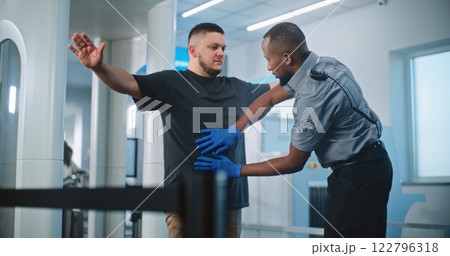 Security Officers Inspecting Adult Man with Metal Detector Scanner for Flight, Finding Mobile Phone 122796318