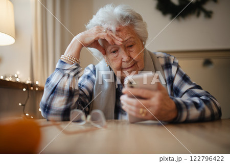 Elderly woman struggling to use smartphone, looking confused. 122796422