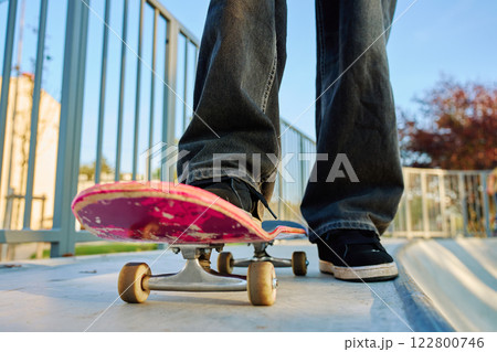 Skateboarder riding on pink skateboard at skatepark Skateboarder riding on pink skateboard at skatepark 122800746