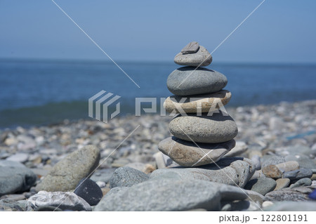 Balancing rocks on a pebble beach during sunset. Smooth pebbles on the beach against the background of the sea and sunlight, creating a side effect on the water. High quality photo Balancing rocks on a pebble beach during sunset. Smooth pebbles on the beach against the background of the sea and sunlight, creating a side effect on the water. High quality photo 122801191