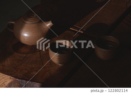 Tea drinking in wabi sabi Japanese style features brown clay cups and a teapot on a wooden solid oak tea table 122802114