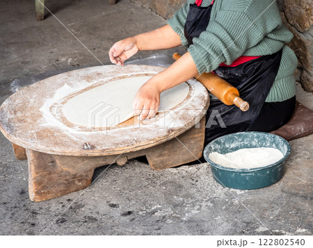 woman takes flattened dough from low table woman takes flattened dough from low table 122802540