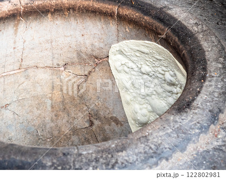 rolled out dough is stuck to hot wall of tandoor 122802981