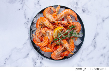 Freshly frozen shrimp on ice, with lemon and rosemary, on the marble table, top view, no people 122803067