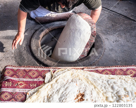 woman sticks raw lavash dough to wall of tandoor woman sticks raw lavash dough to wall of tandoor 122803135