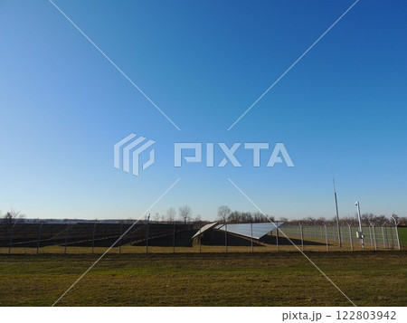 side view of a large solar panel complex in a field on a clear day, industrial production of solar energy for conversion to electricity, protected area with photovoltaic panels side view of a large solar panel complex in a field on a clear day, industrial production of solar energy for conversion to electricity, protected area with photovoltaic panels 122803942