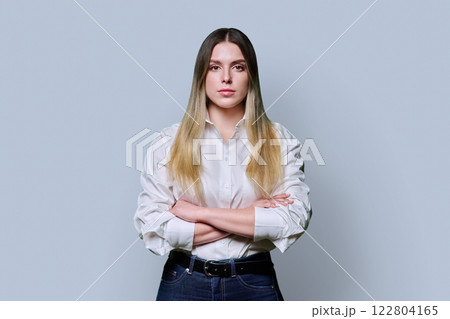 Portrait of young confident serious woman in white shirt on gray background 122804165