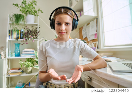 Webcam view of talking teenage girl in headphones in home room Webcam view of talking teenage girl in headphones in home room 122804440