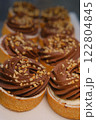 chocolate tart crushed peanut topping in buttery shortcrust pastry basket on white plate placed on counter perfect for dessert lovers indulgent treat rich texture sweet pastry close up festive 122804845