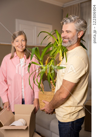 Happy senior couple unpacking cardboard boxes together in their new apartment 122806904