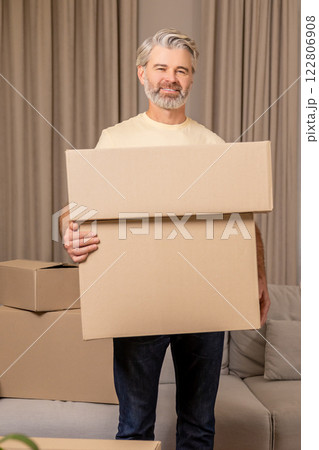Happy senior bearded man packing cardboard boxes during relocation 122806908