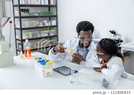Male teacher of science showing to a school girl how to use vacutainers Male teacher of science showing to a school girl how to use vacutainers 122806935