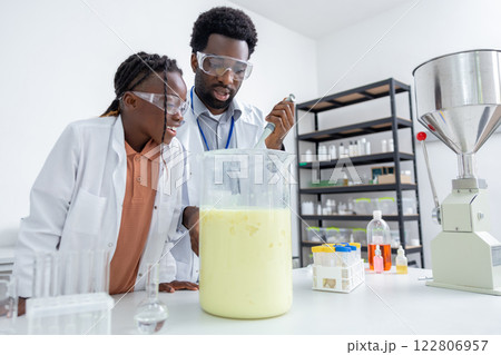 Male teacher and a school girl working on chemistry experiment in a school lab Male teacher and a school girl working on chemistry experiment in a school lab 122806957