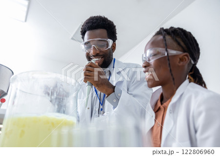 Male teacher and a school girl working on chemistry experiment in a school lab 122806960