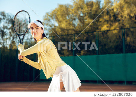 Competitive woman tennis player during game training at open air tennis court on sunny day 122807020
