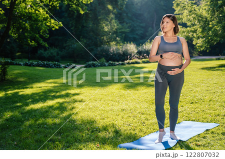 Pregnant woman on a third trimester holding her belly and looking thoughtful 122807032