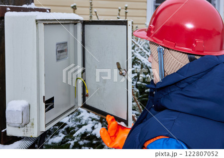 Field technician inspects an electrical meter box outdoors. 122807052