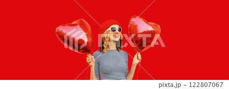 Happy joyful smile young woman holding red heart shaped balloon isolated on studio background Happy joyful smile young woman holding red heart shaped balloon isolated on studio background 122807067