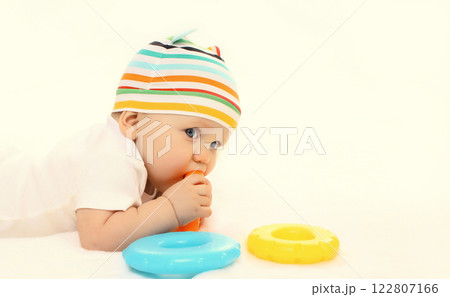 Happy little baby playing with toys sitting on floor on white studio background 122807166