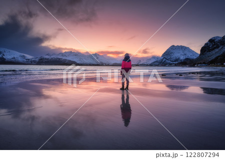 Woman on the arctic sandy beach, snowy mountains and red sky Woman on the arctic sandy beach, snowy mountains and red sky 122807294
