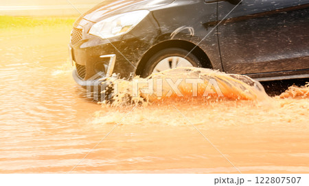 A vehicle navigates through muddy floodwater, depicting urban resilience and the impact of heavy rain. This image highlights extreme weather, climate change, and transportation challenges. A vehicle navigates through muddy floodwater, depicting urban resilience and the impact of heavy rain. This image highlights extreme weather, climate change, and transportation challenges. 122807507