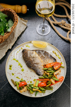 Grilled sea bream fillet with vegetables and lemon, plated with elegant garnish, fine dining style 122807802